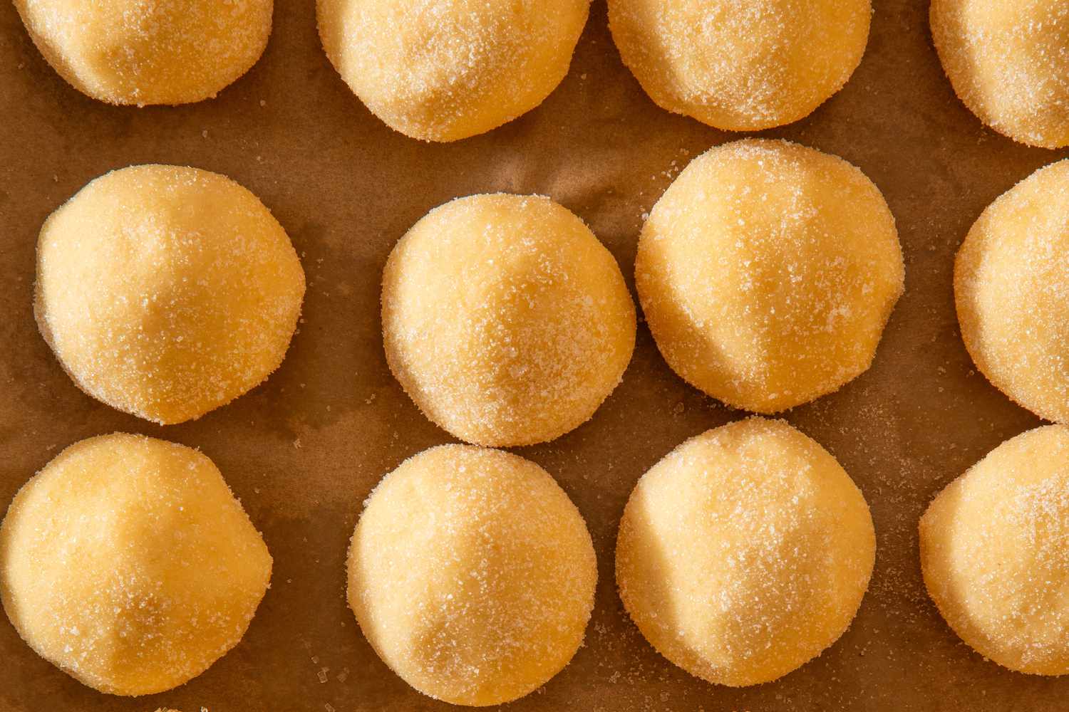 Rolled smash sugar cookie dough balls on a parchment paper lined baking sheet