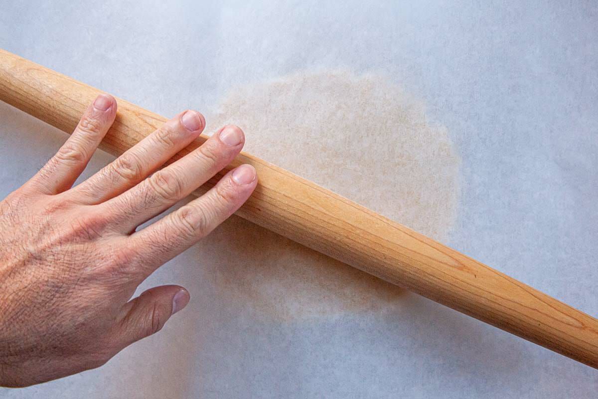 Rolling pin rolls out dough for Homemade Sugar Cookies that is covered in parchment.