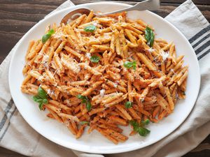 Penne alla Vodka in a Plate with a Spoon over a Kitchen Towel