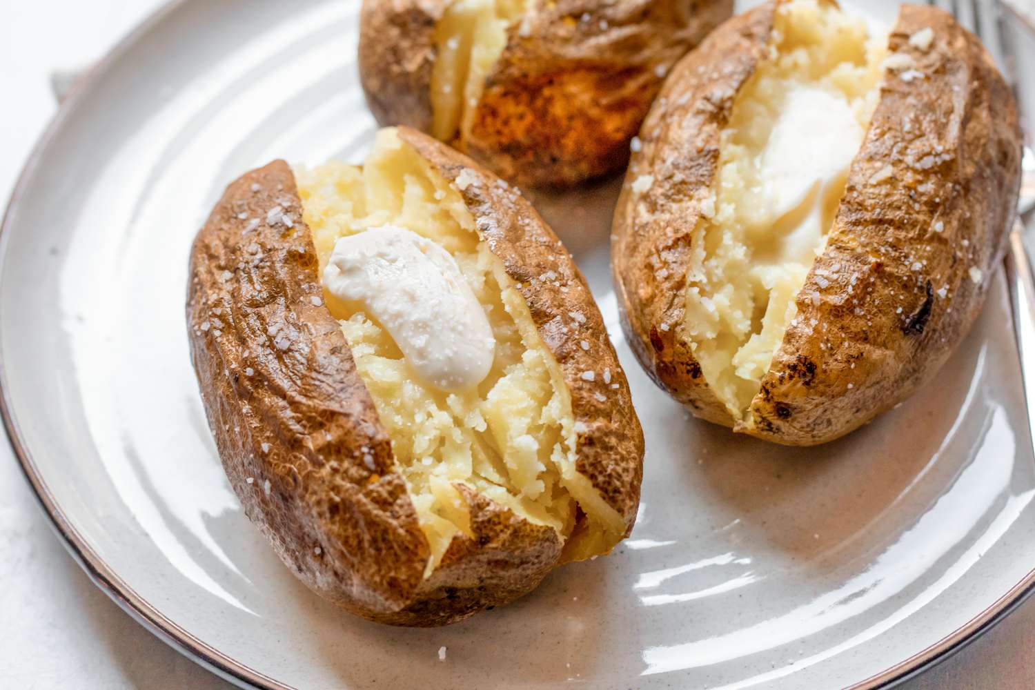 Baked potatoes with sour cream and salt (all on a plate)