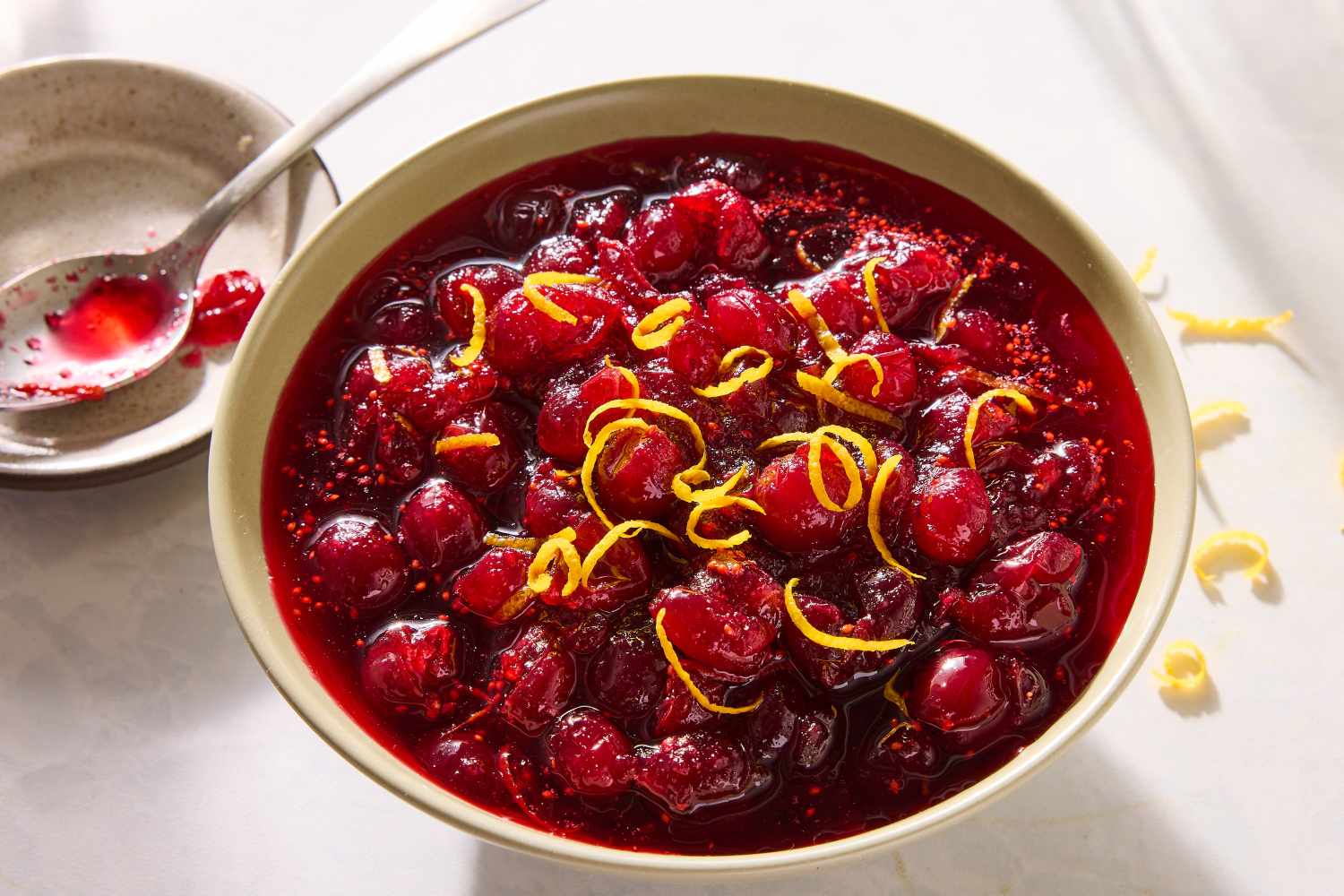 A bowl with cranberry sauce inside, garnished with orange zest and ready to serve