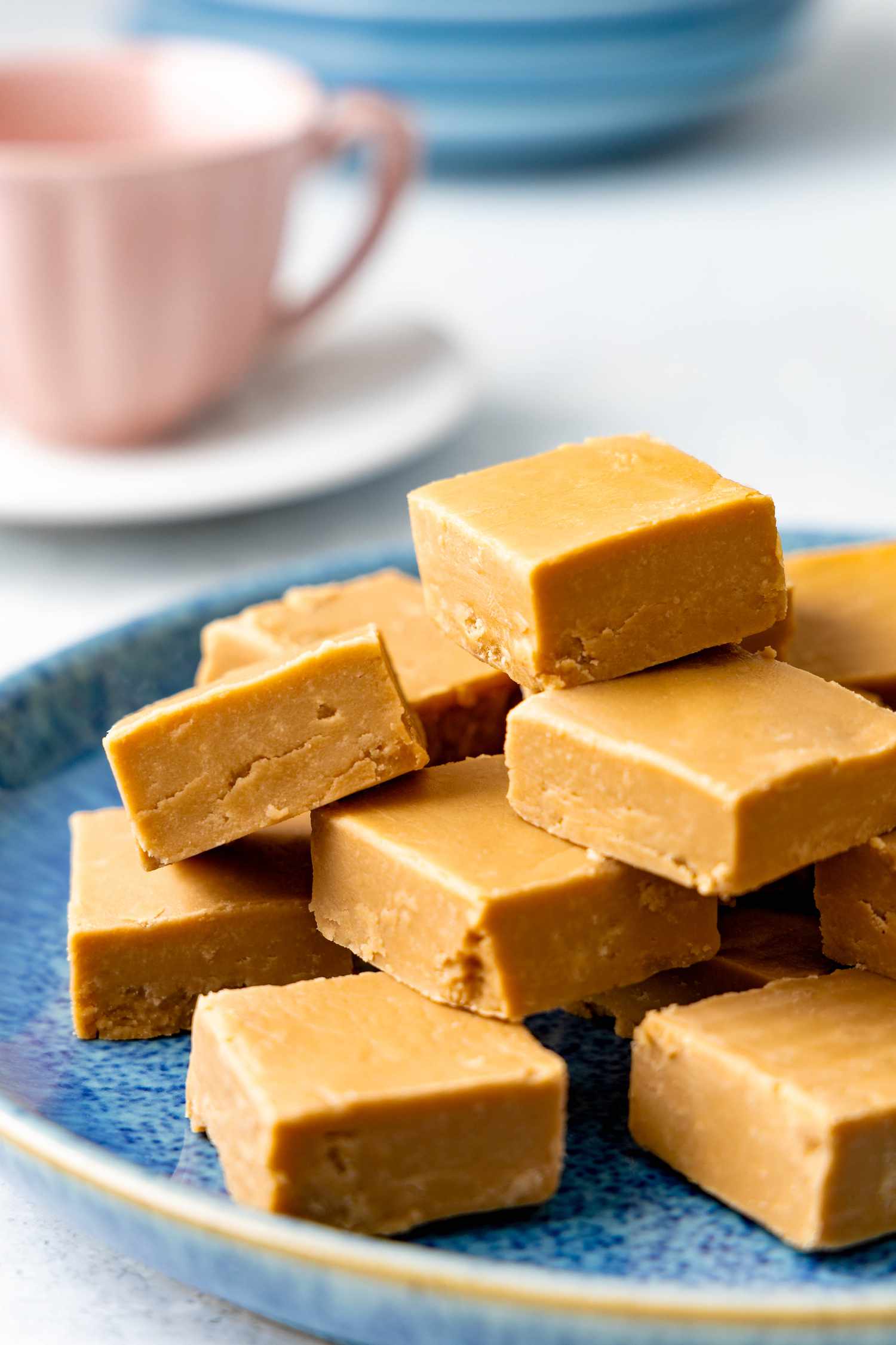 Penuche on a plate, and in the background, a teacup and a bowl