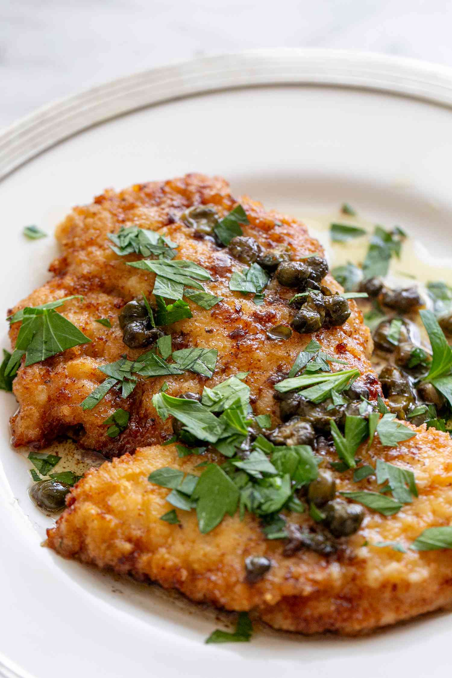 A helping of chicken piccata on a plate topped with sauce