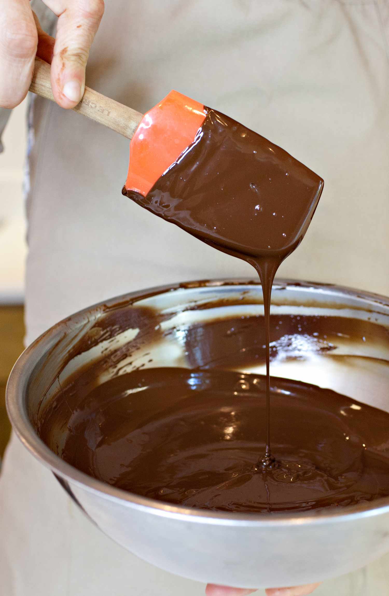 Chocolate Dripping Off the Side of a Spatula into a Bowl with More Melted Chocolate for How to Temper Chocolate