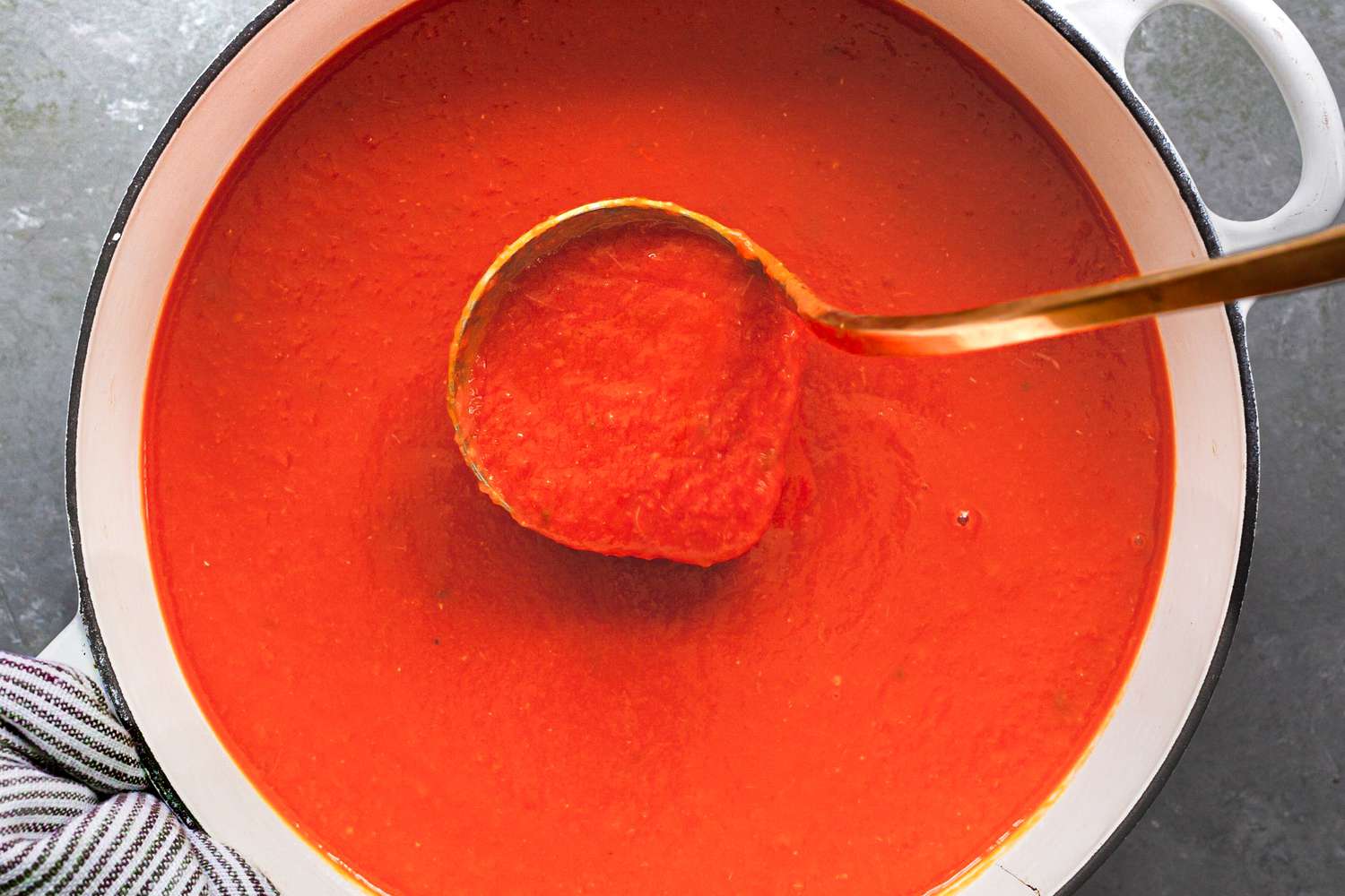 Pot of tomato sauce with a ladle in it