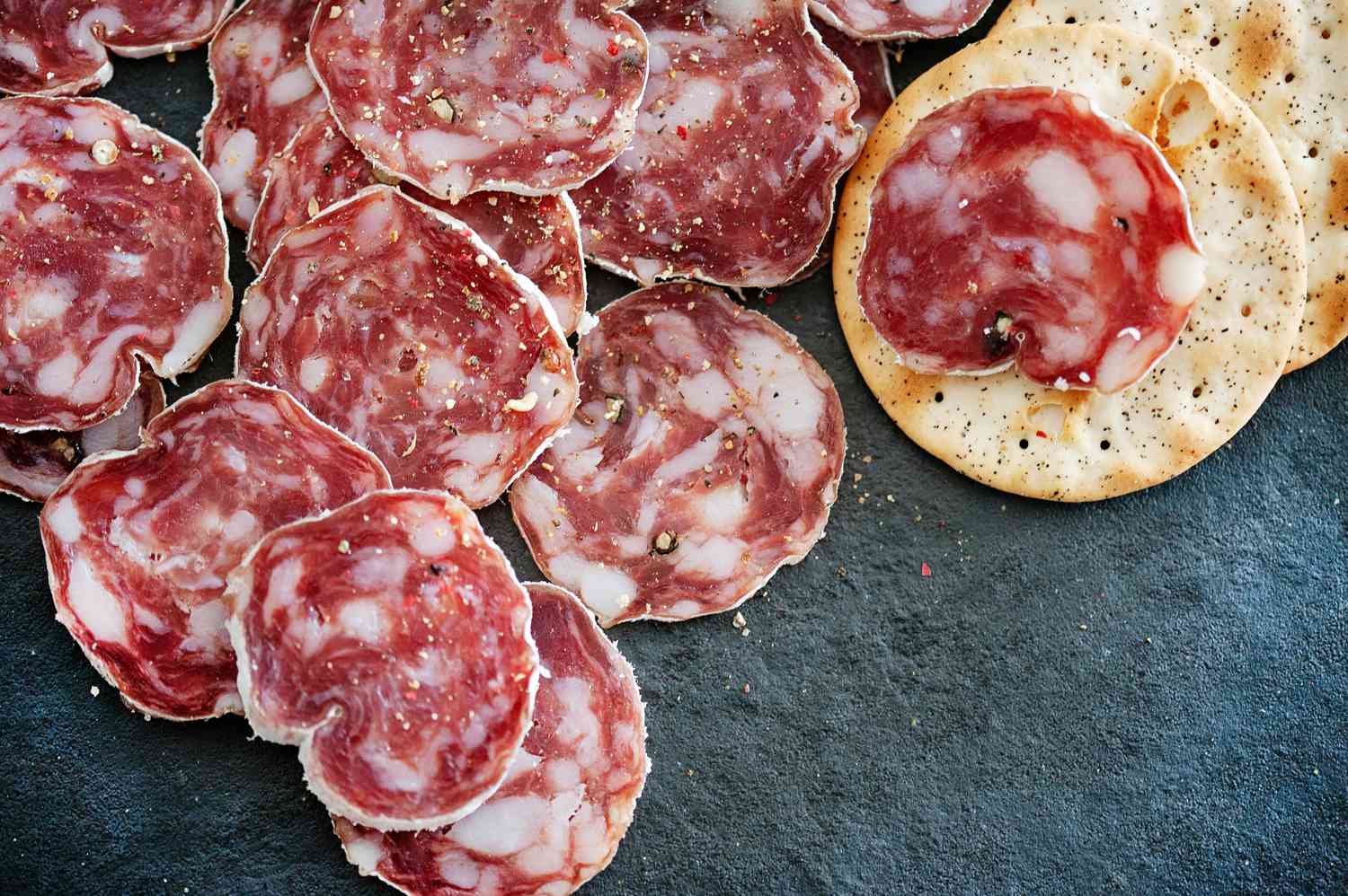 Sliced soppressata and crackers on slate board