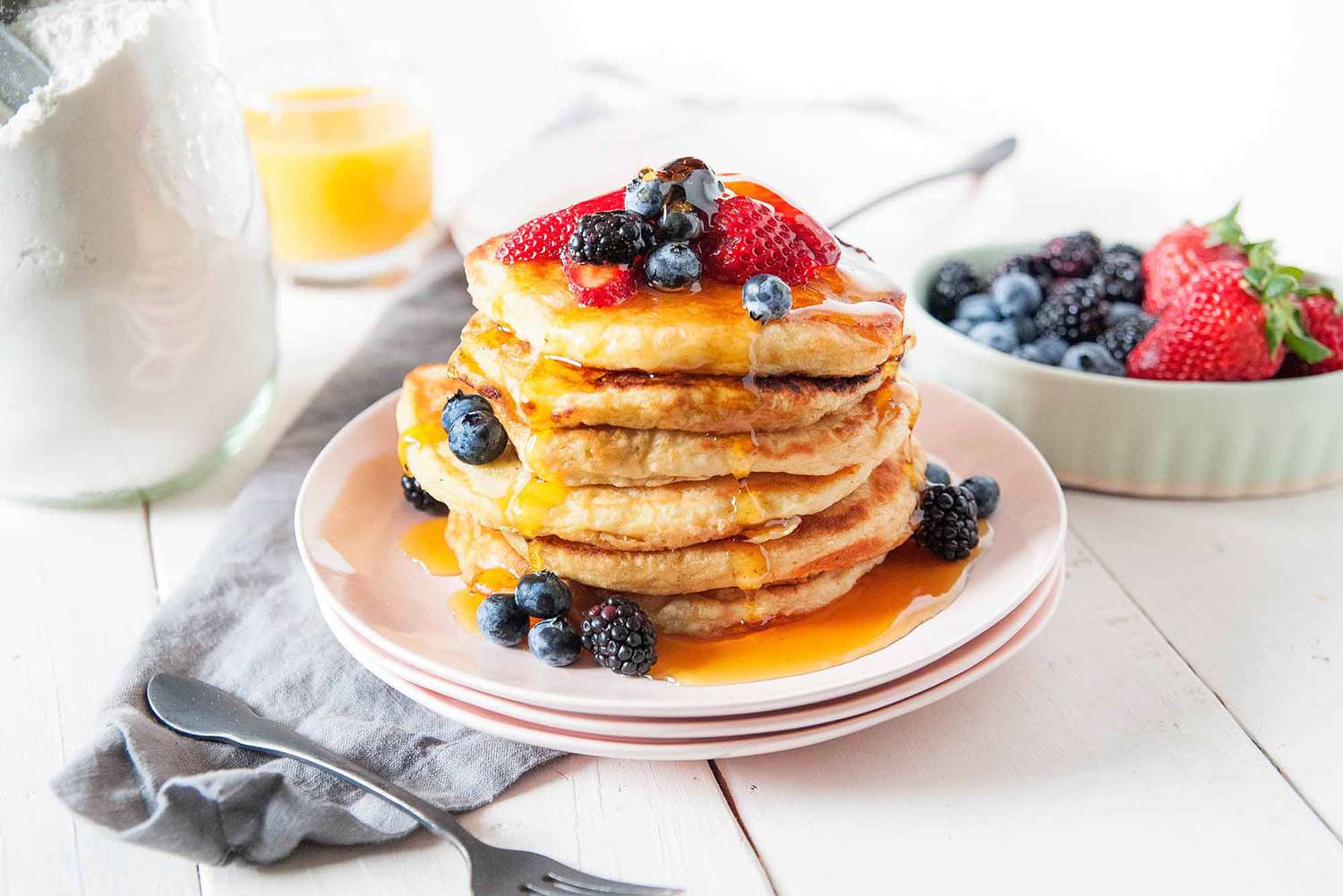 Stack of pancakes drenched in syrup with berries on top