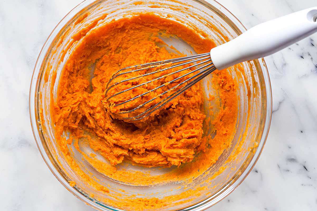 Wisking the sweet potatoes for a classic sweet potato pie with a white whisk.