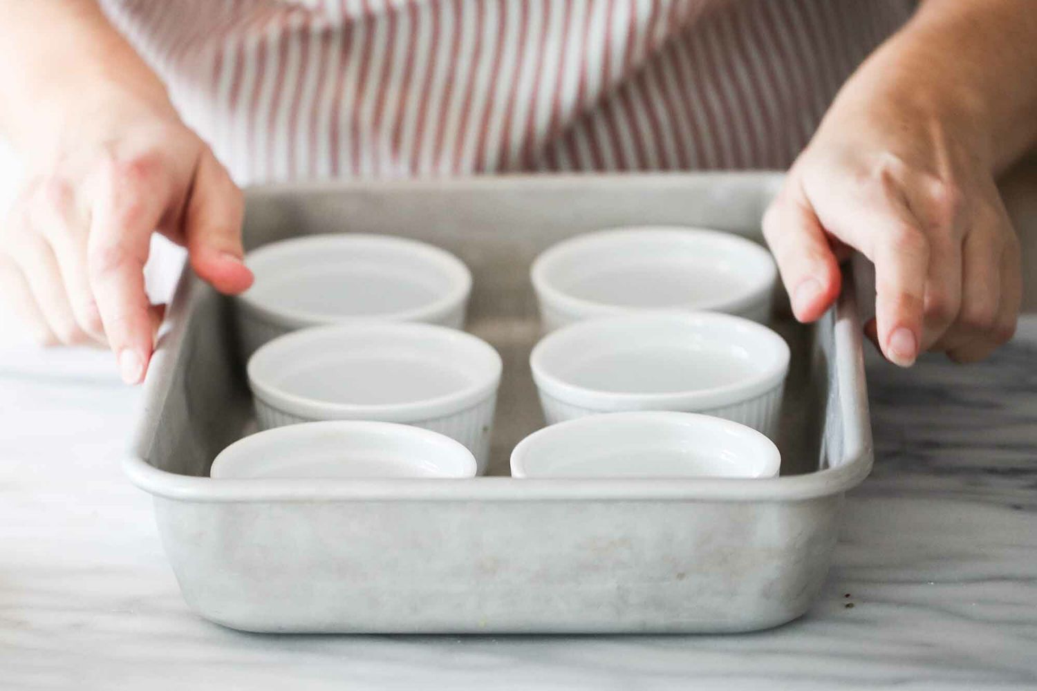Six ramekins in a pan for creme brulee