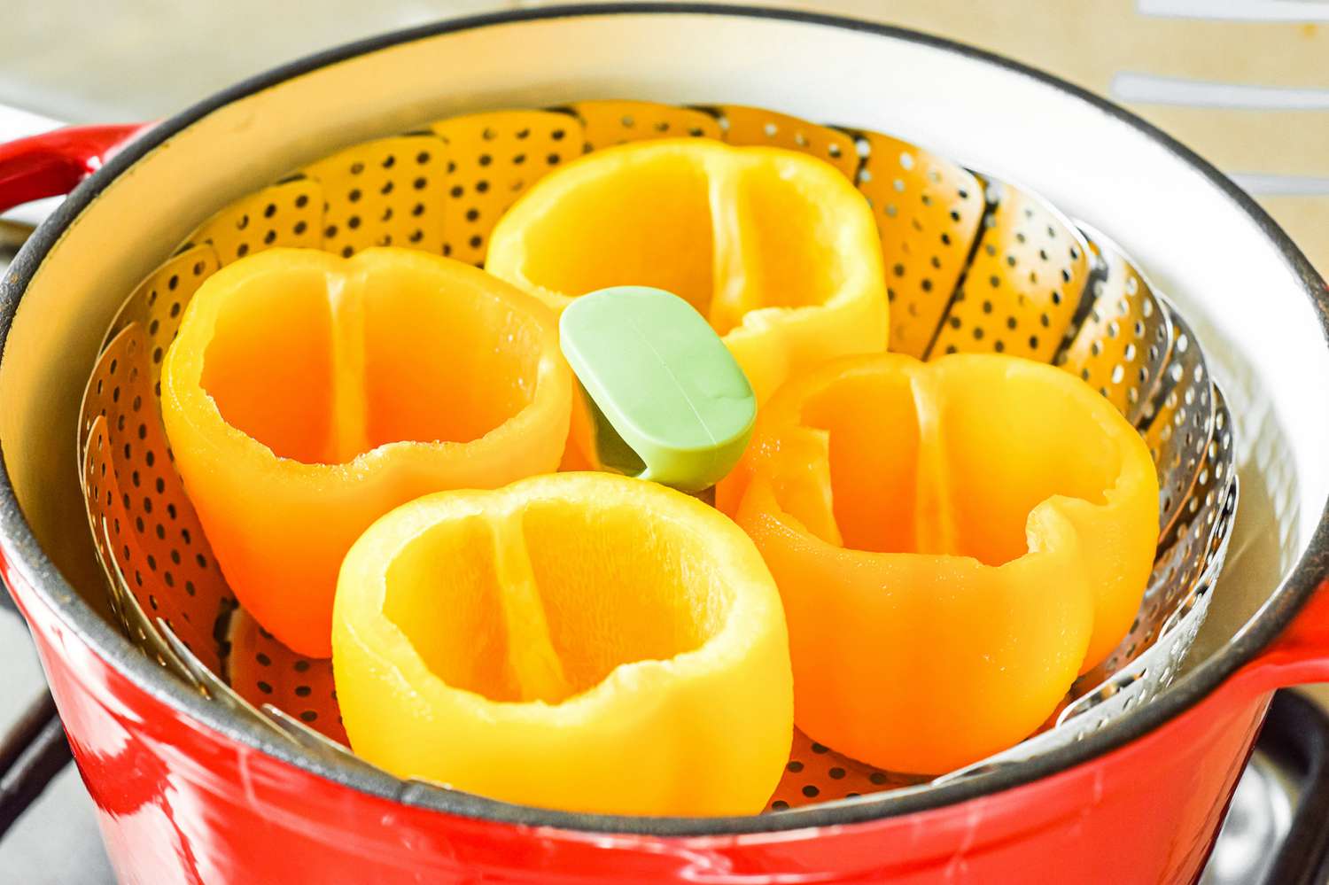 Tops and seeds removed from yellow bell peppers and set in a steamer basket to make stuffed bell pepper recipe.