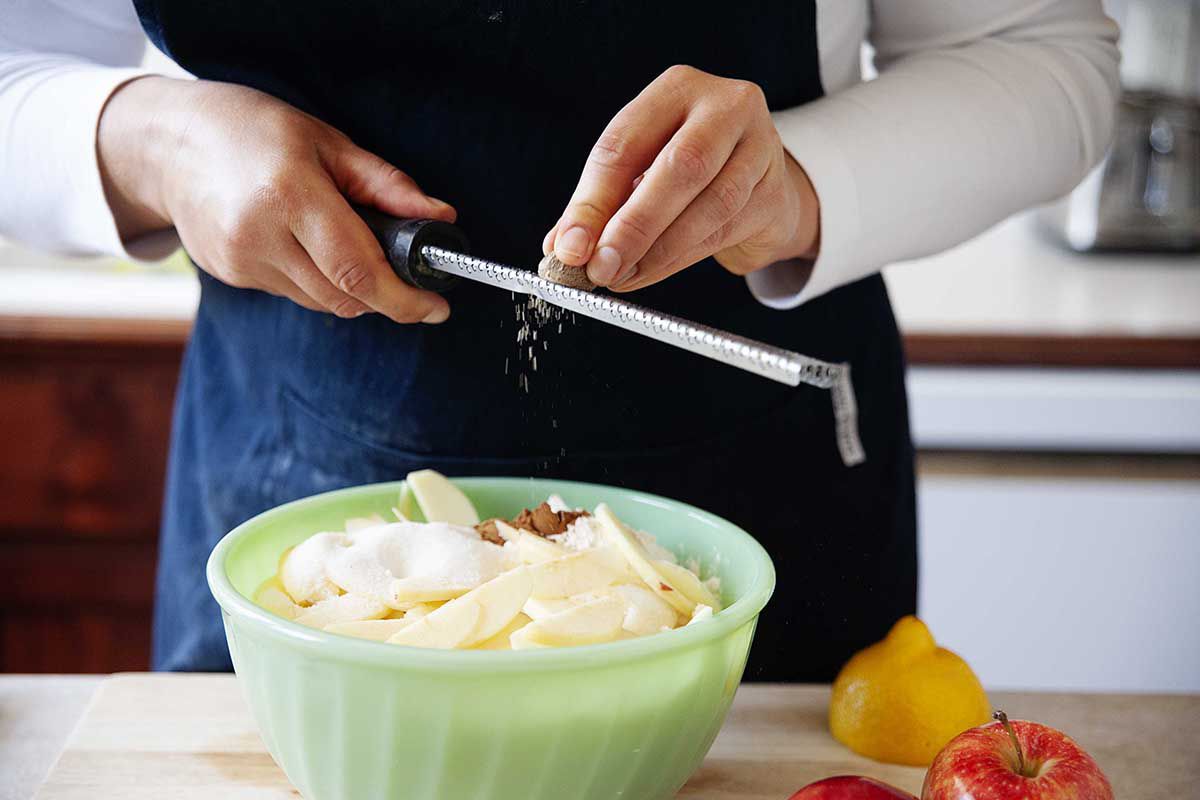 Woman grating nutmeg into a bowl.