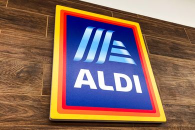 A sign with the ALDI logo mounted on a woodentextured wall