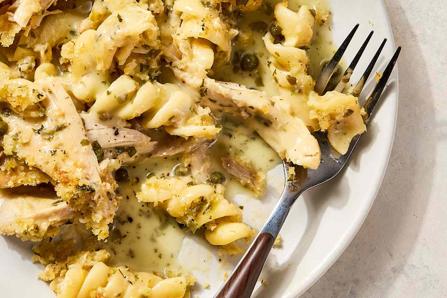 A plate of chicken piccata noodle casserole with a fork beside it