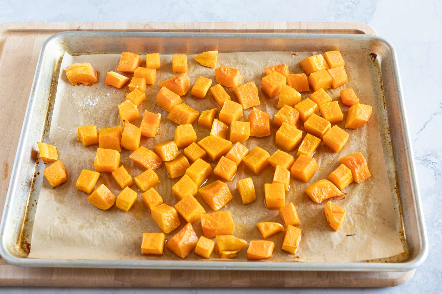 Roasted cubes of butternut squash on a sheet pan