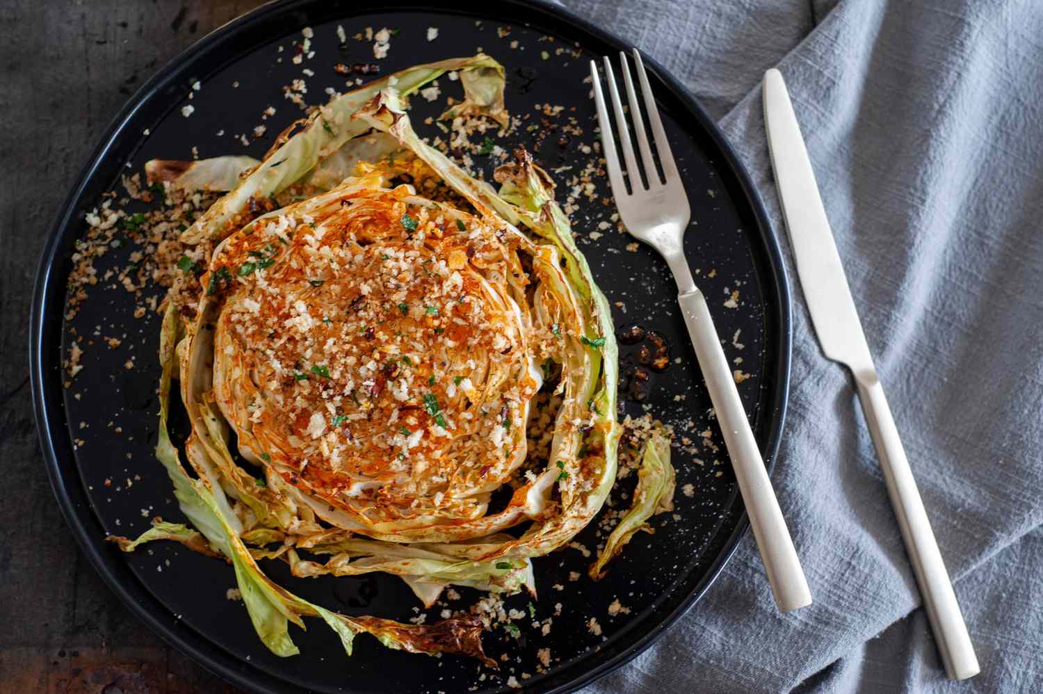Easy roasted cabbage with breadcrumbs on a black plate with a fork.