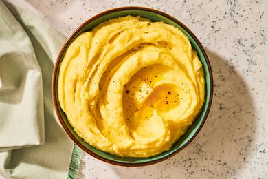 A serving bowl of mashed potatoes with butter melting in the center