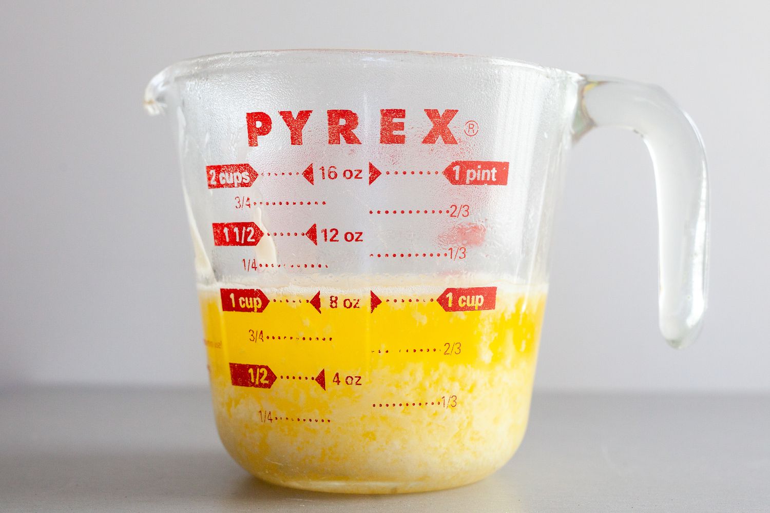 Side view of melted butter in a liquid measuring cup to make béarnaise sauce.
