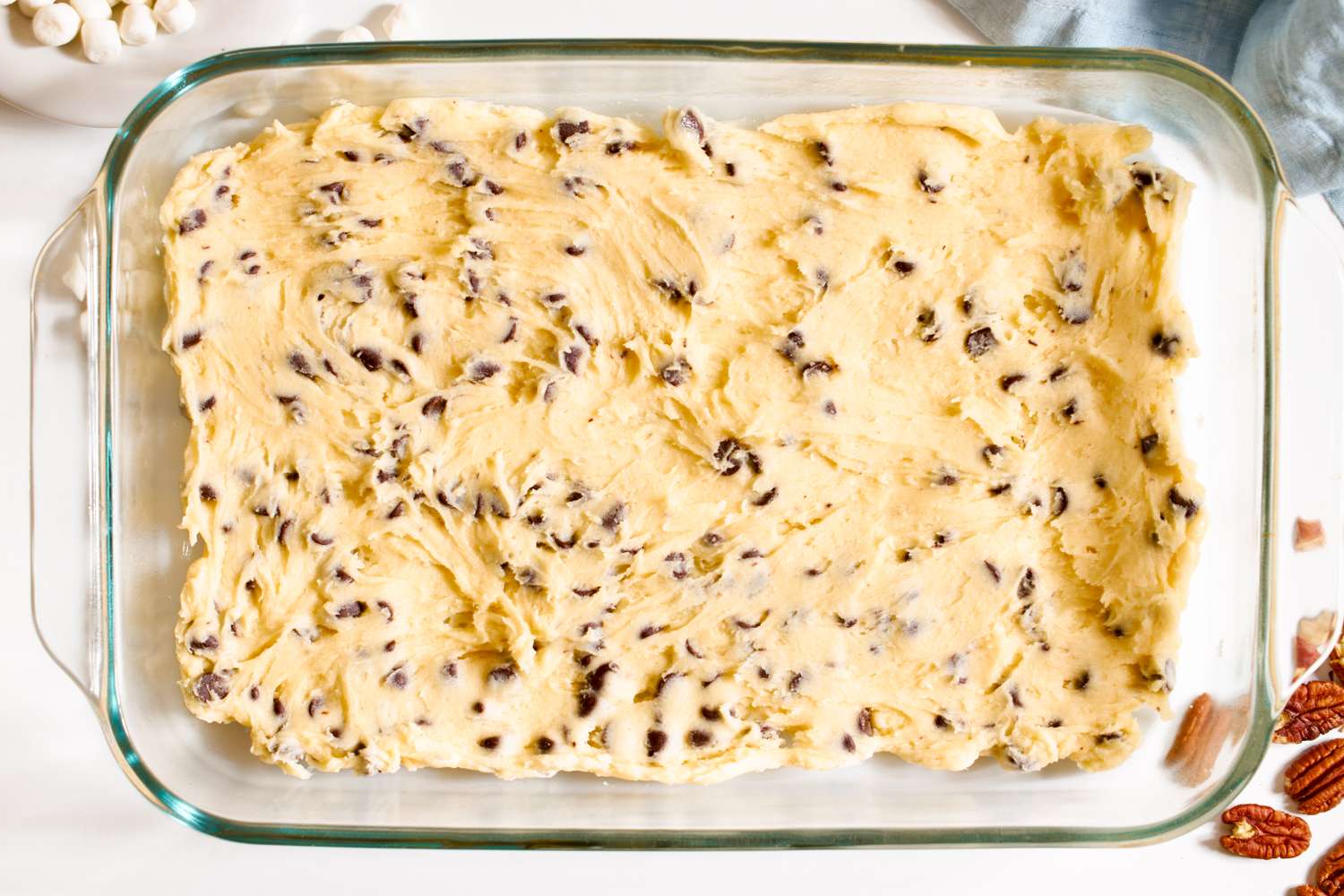 Cookie dough pressed into rectangular glass baking dish for mud hen bars recipe