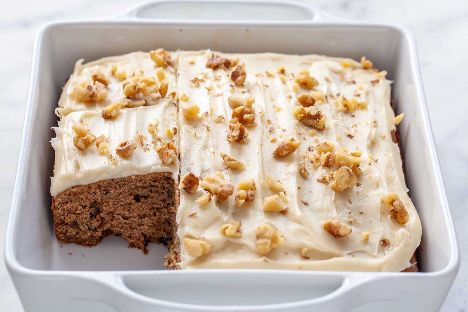 Applesauce cake, frosted and with a piece removed.