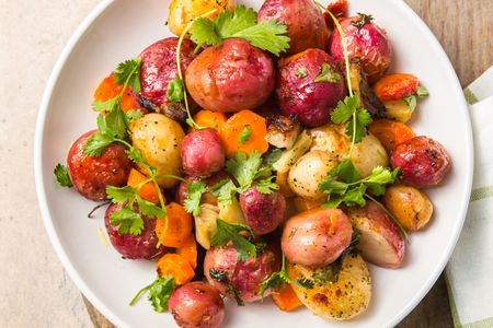 A plate of roasted root vegetables with garnish including potatoes and carrots