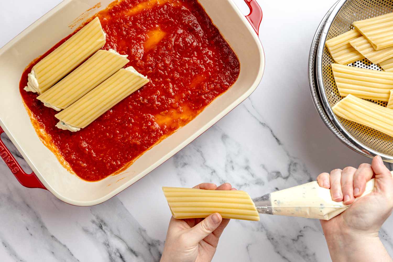 Filling Manicotti (L to R): Filled Manicotti on a Layer of Marinara Sauce in a Casserole Dish, Manicotti Filled Using the Piping Bag, and a Colander With Unfilled Manicotti