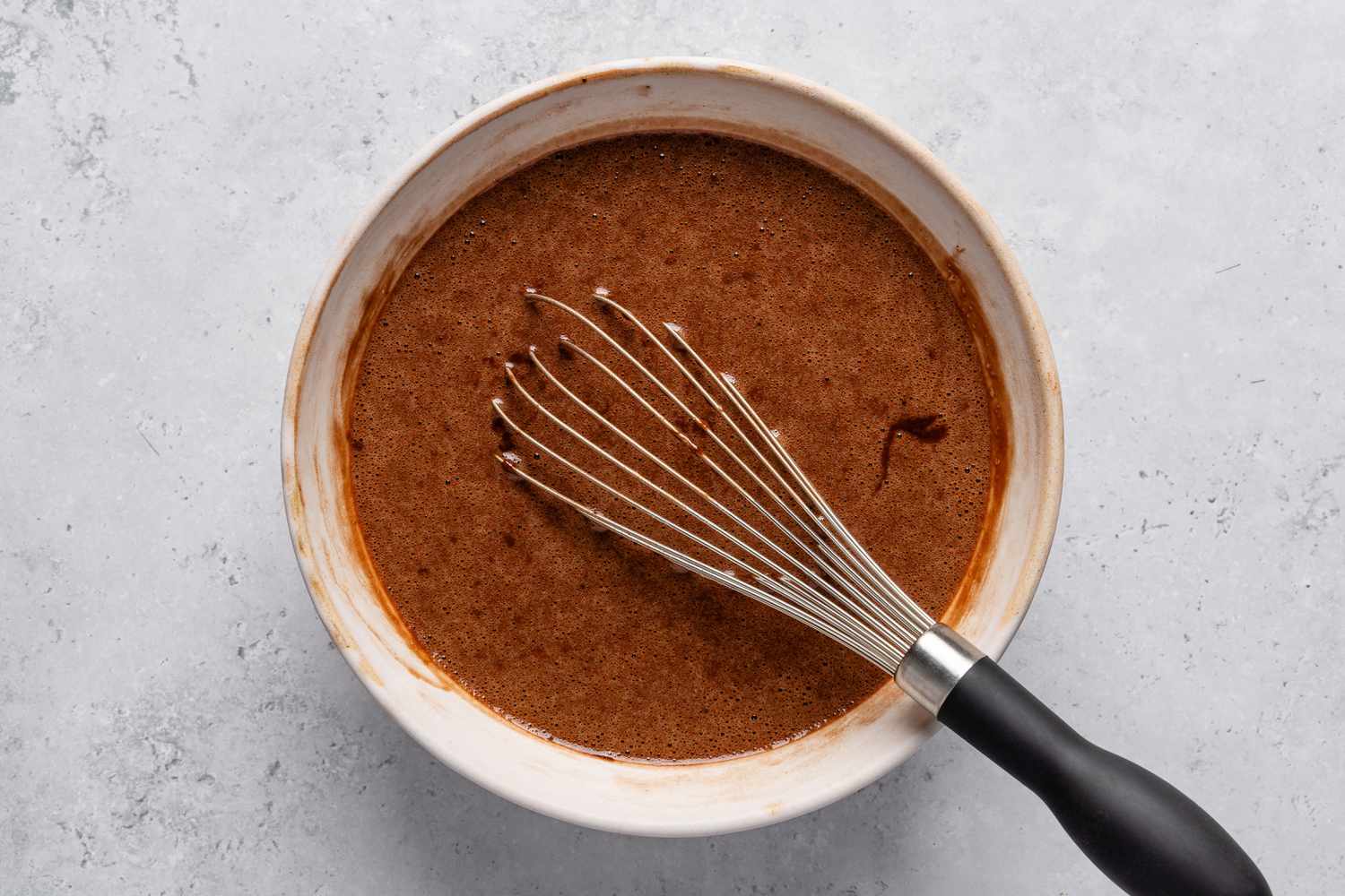 A whisk in a bowl with the batter for the Chocolate stout loaf cake recipe