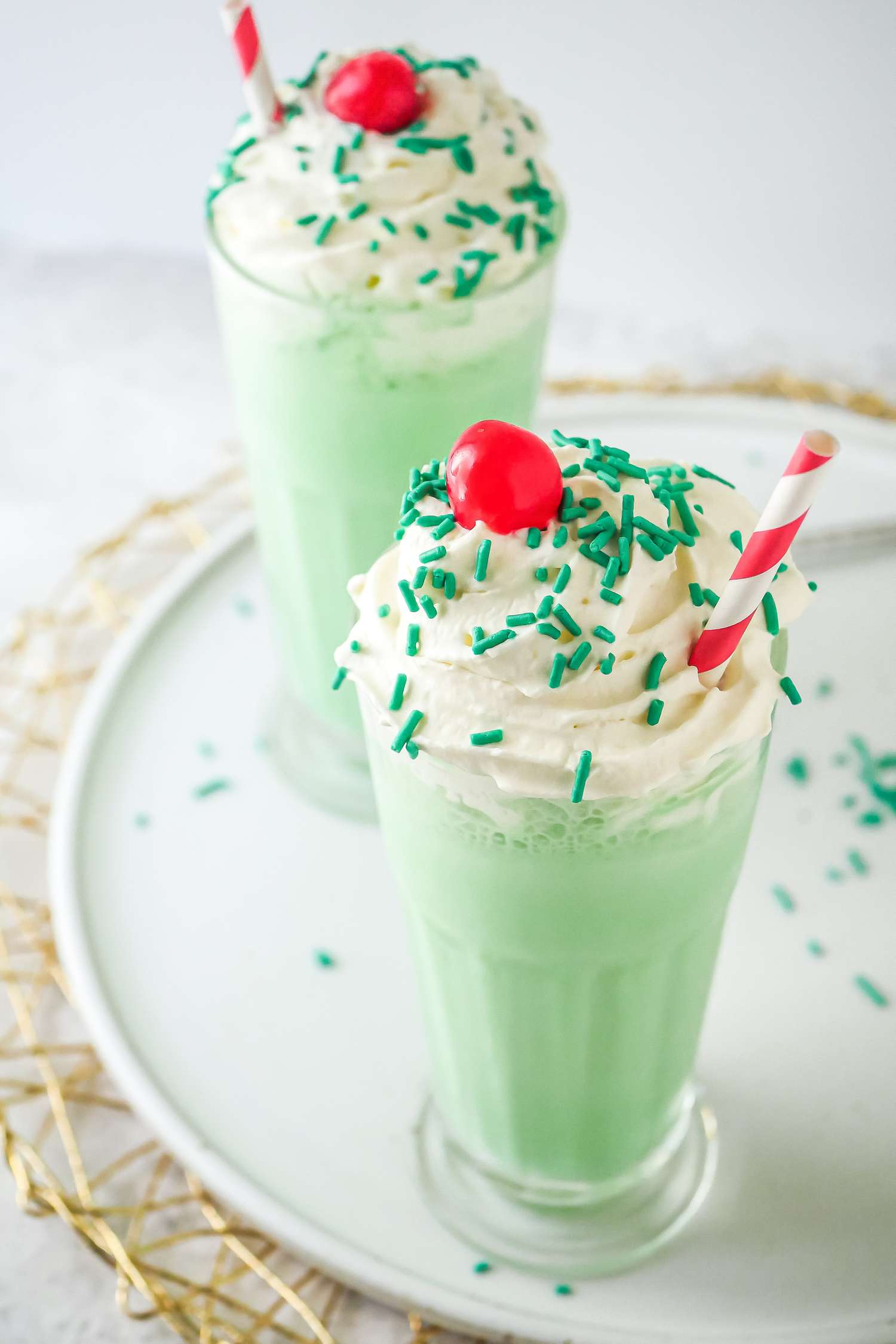 Two McDonald’s Shamrock Shakes in frosty glasses with cherries and straws.