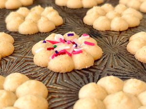 Spritz cookies arranged on a decorative tray one cookie topped with colorful sprinkles