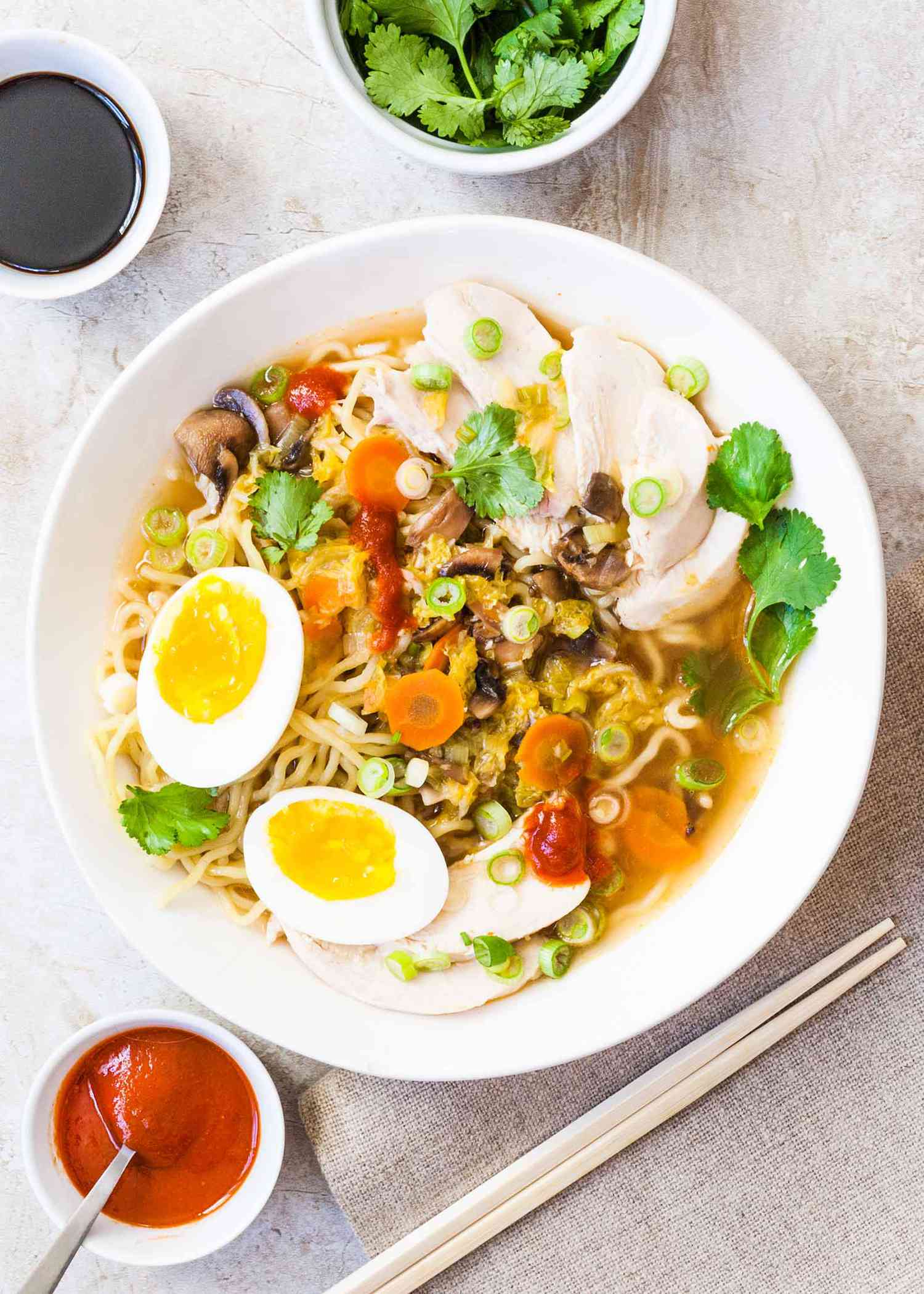 Quick Ramen Soup With Chicken, noodles, and poached eggs in a round bowl with chopsticks.