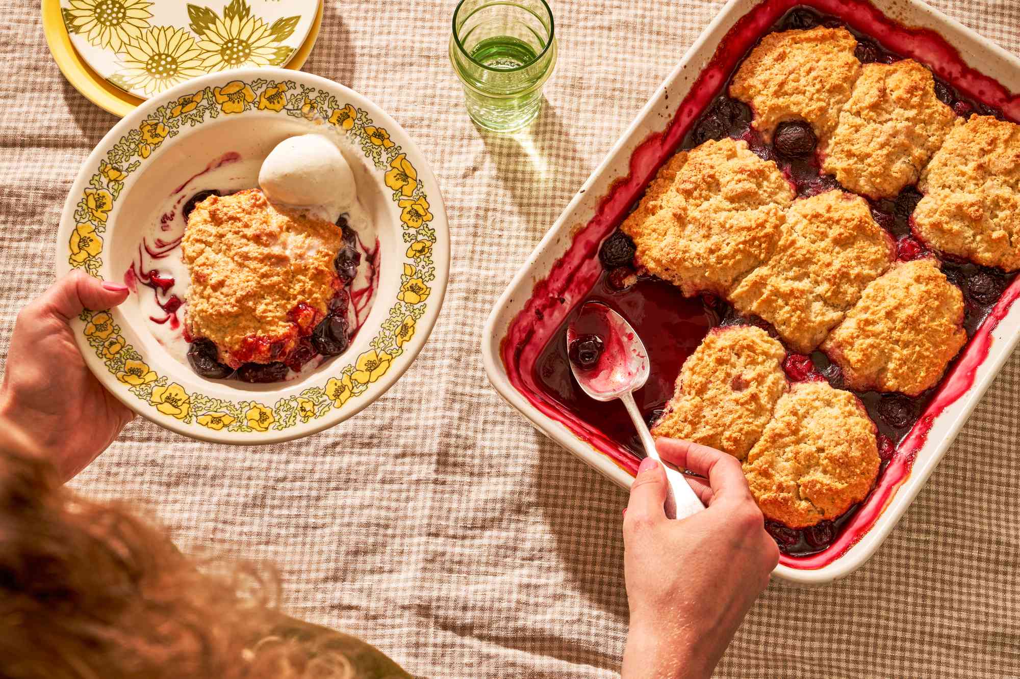 Woman serving cherry cobbler from a baking dish