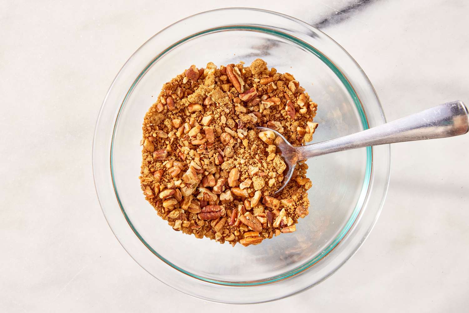 overhead view of chopped pecans in a bowl with a spoon for Sock It to Me Cake