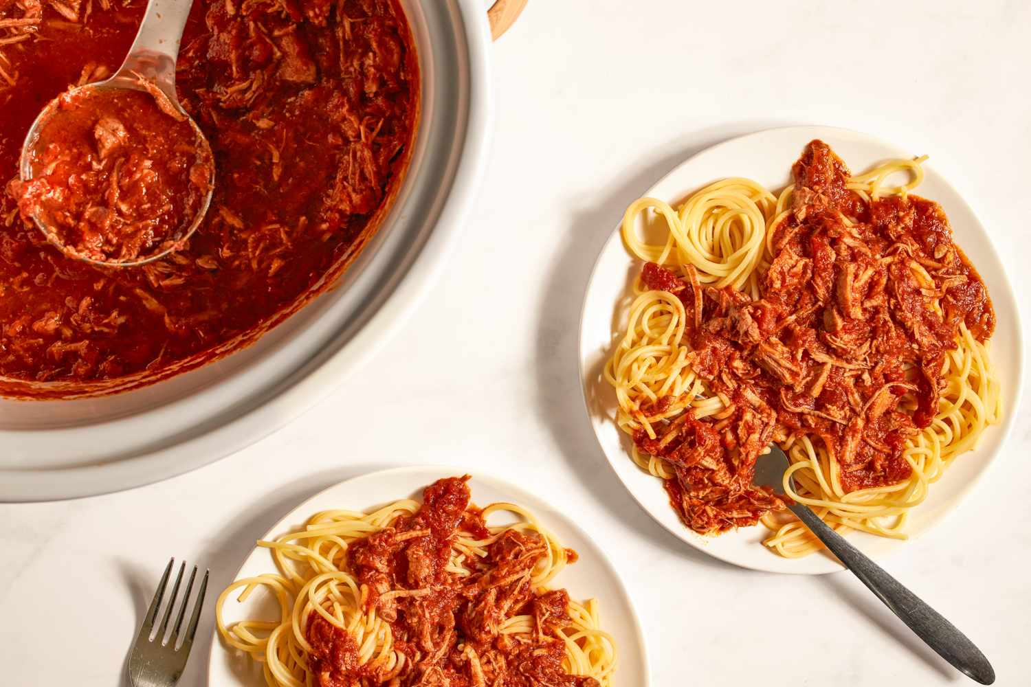 Bowls of spaghetti with red meat sauce served from a pot