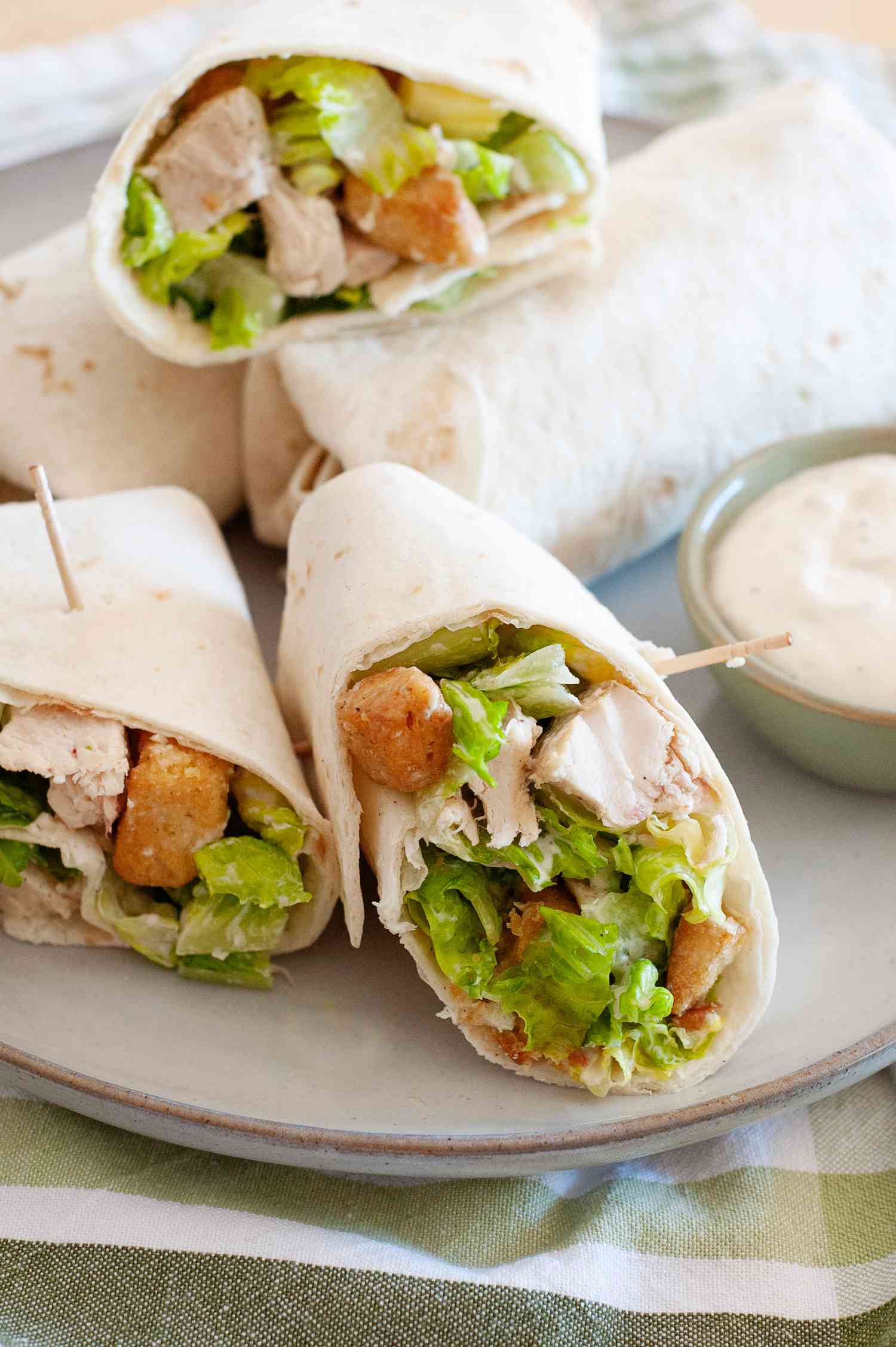 Chicken Caesar Wraps Cut in Half on a Plate with a Small Bowl of Dressing
