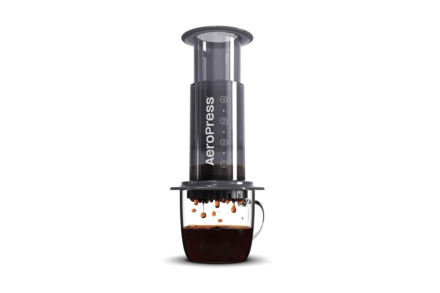The AeroPress coffee maker sitting atop a clear glass mug with coffee being brewed in it