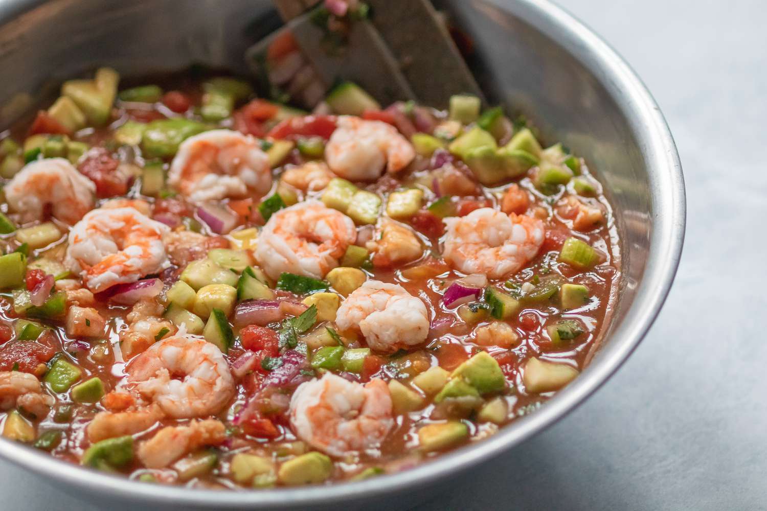 A mixing bowl with ingredients to make a shrimp cocktail with shrimp added 
