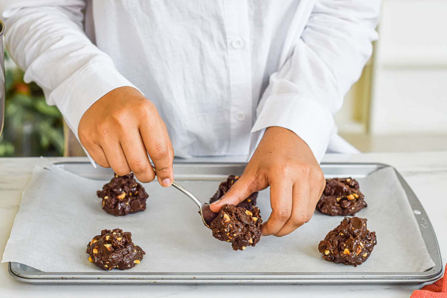 A person scooping nutella cookies onto a baking sheet.