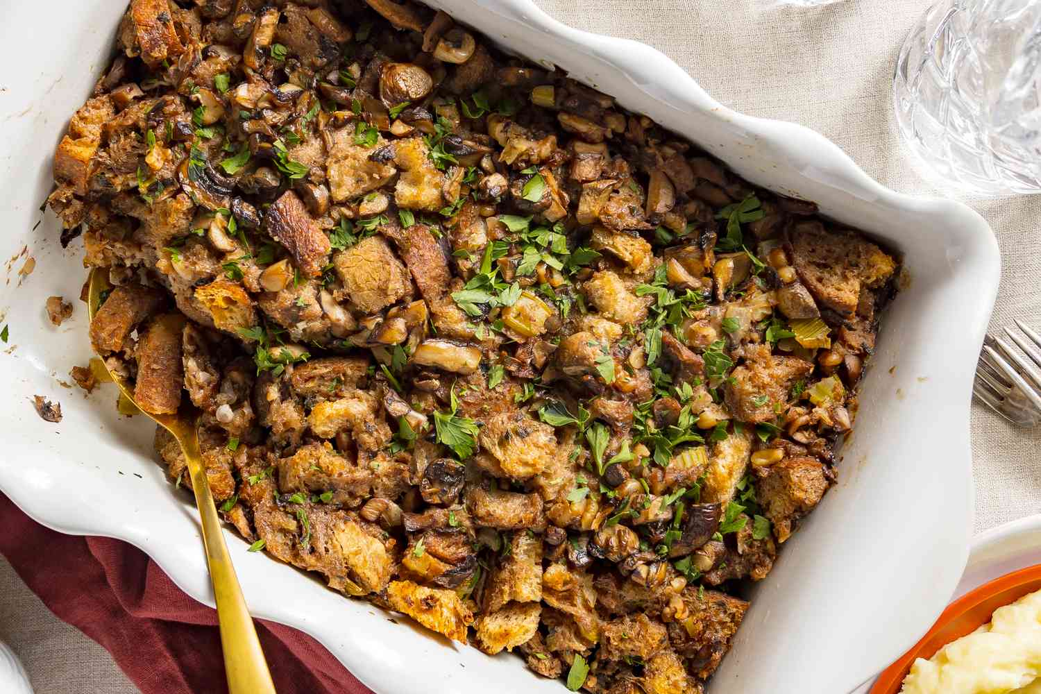 Stuffing in a baking dish, with a serving spoon scooping some stuffing out