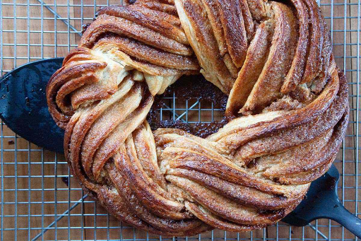 The easy King Cake is transferred to a cooling wrack by two spatulas.