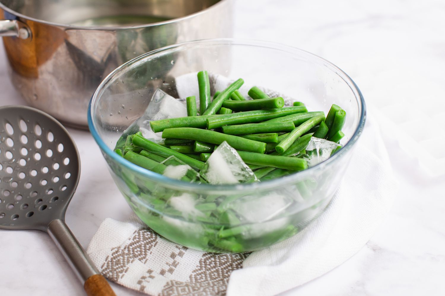 Blanched green beans in a bowl of ice for a green bean salad recipe.
