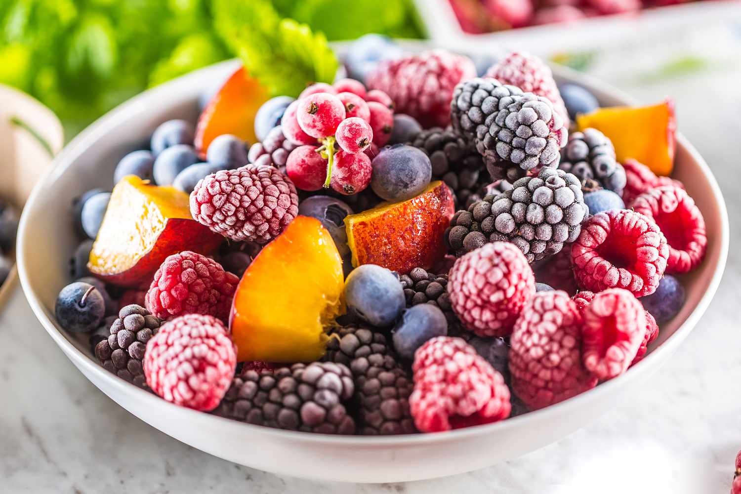bowl of frozen fruits, berries and peach chunks