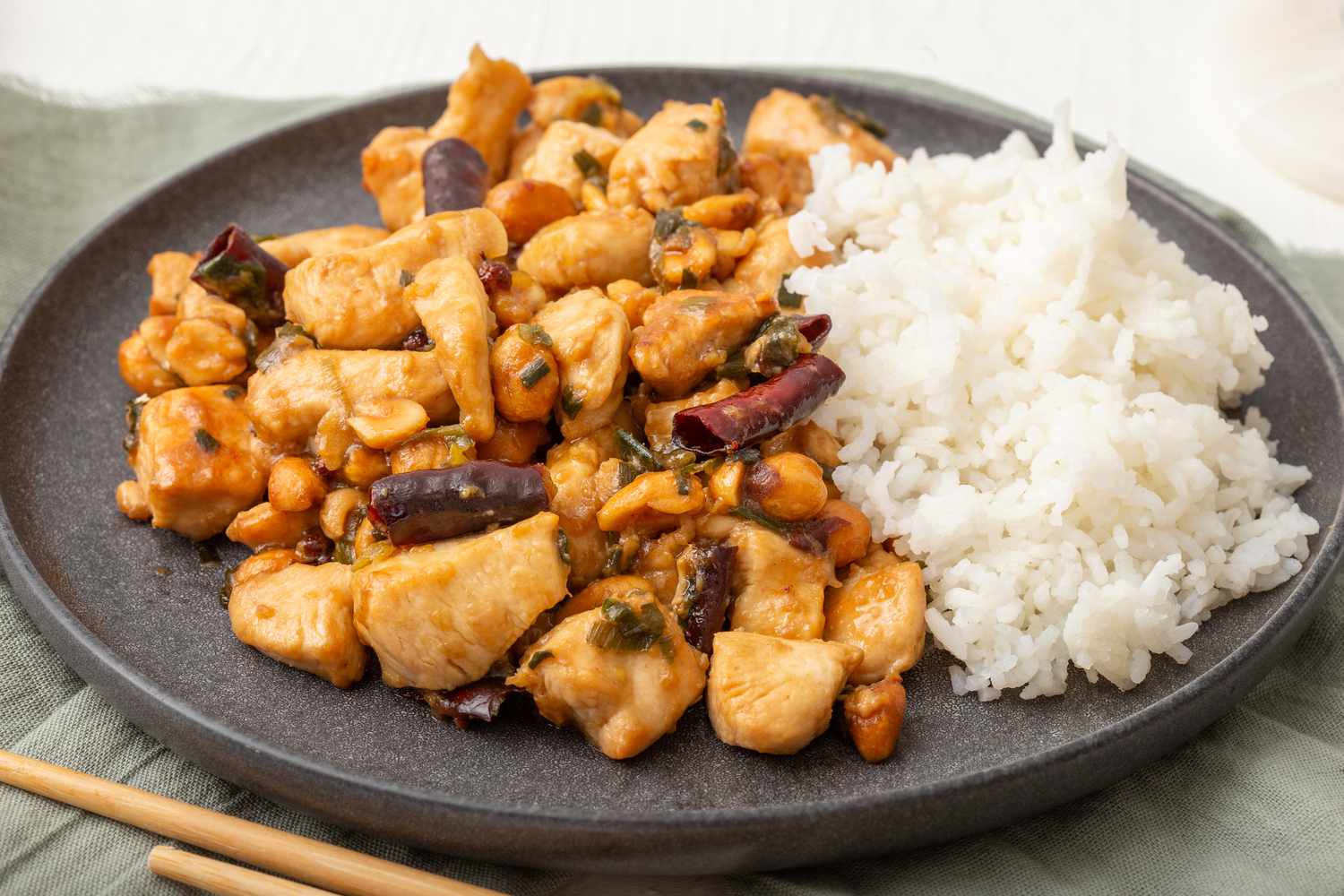 Side view of a plate of kung pao chicken with rice.