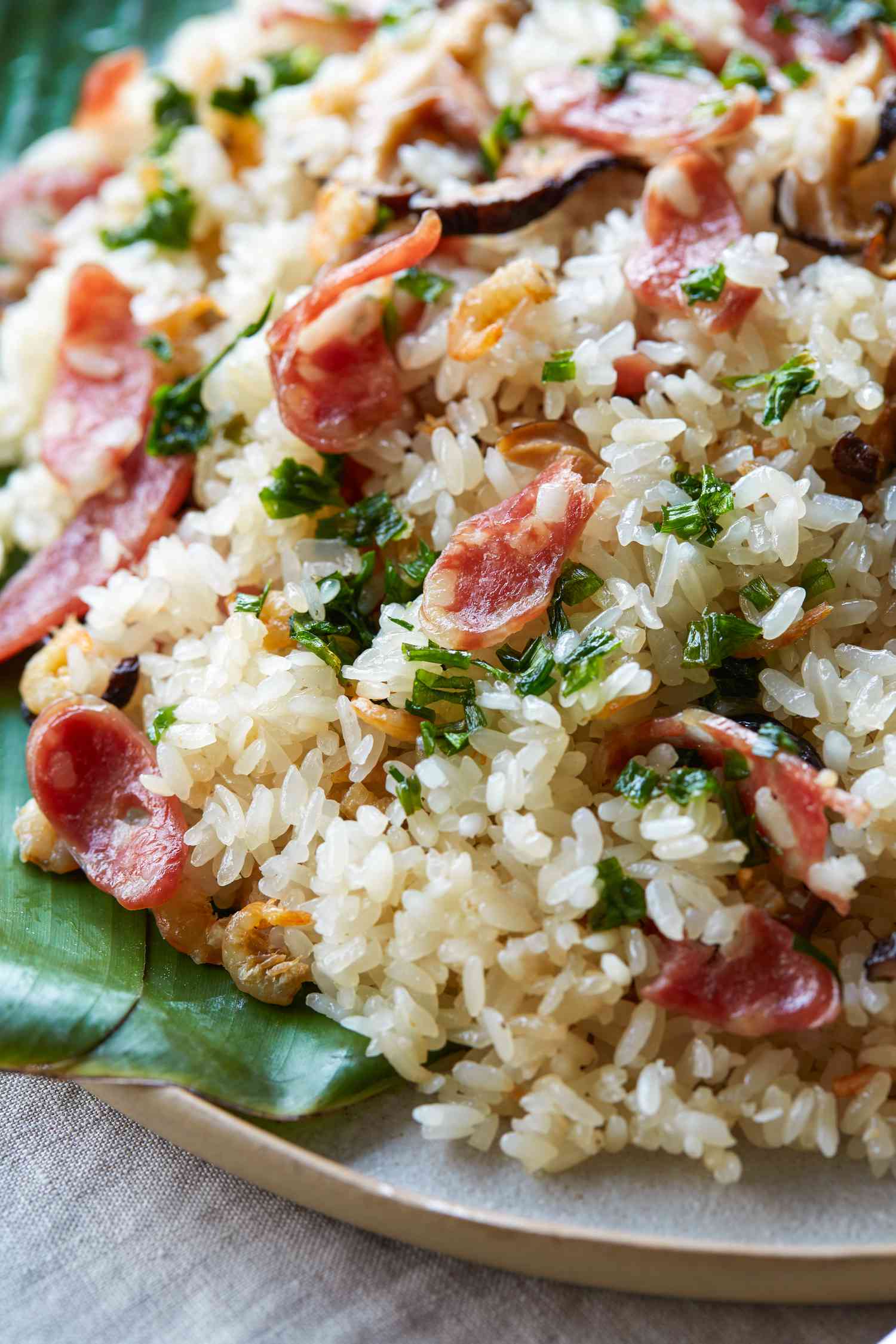 Close up of a platter of sticky rice with lạp xưởng, shrimp, and mushrooms