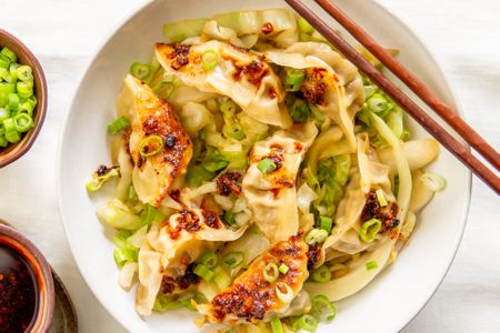 Gyoza with cabbage and green onions served in a bowl with chopsticks