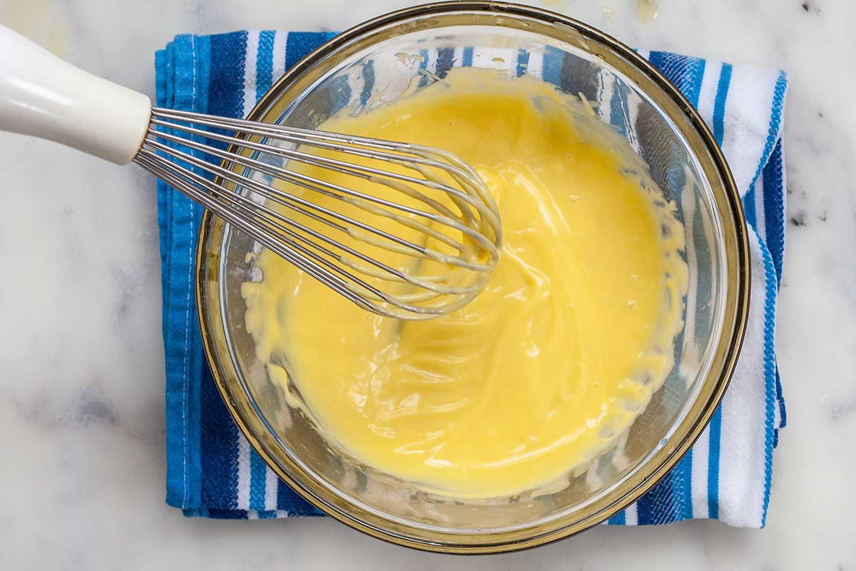 A whisk sits on the side of a small bowl of easy garlic aioli.