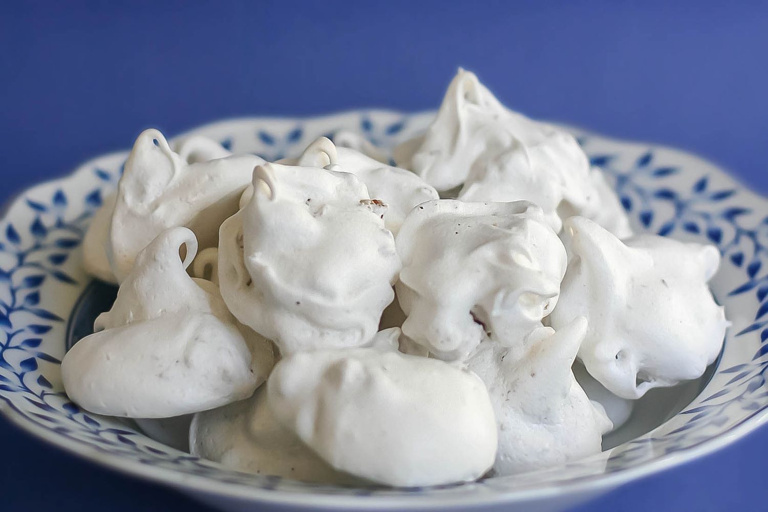 Side shot of a pile of pecan meringue cookies on a plate