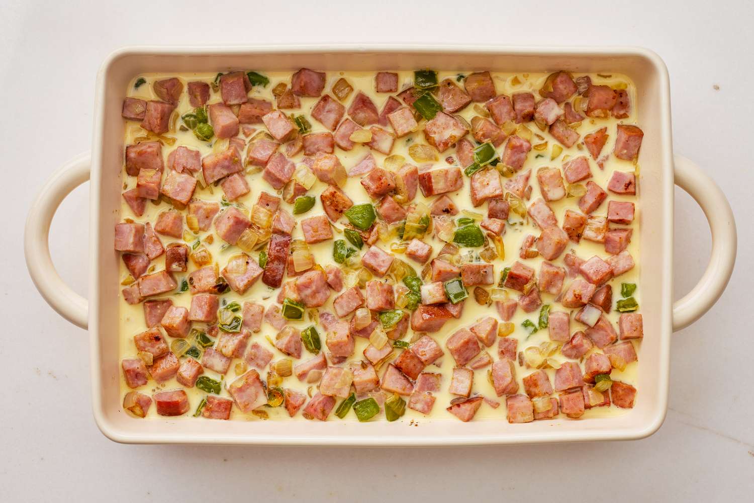 Egg and milk mixture added to casserole dish with the rest of Denver omelette hashbrown casserole recipe ingredients