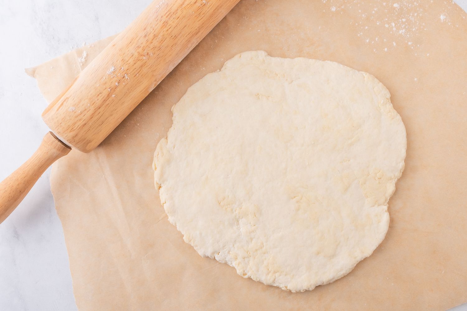 pizza dough rolled out on a piece of parchment paper