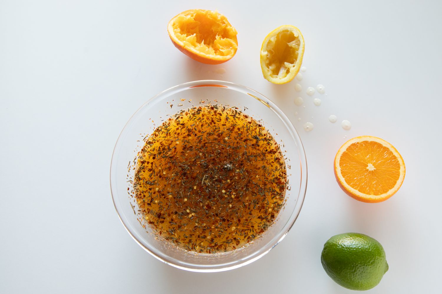 Glass bowl with juiced citrus around it to make a pork rib marinade.