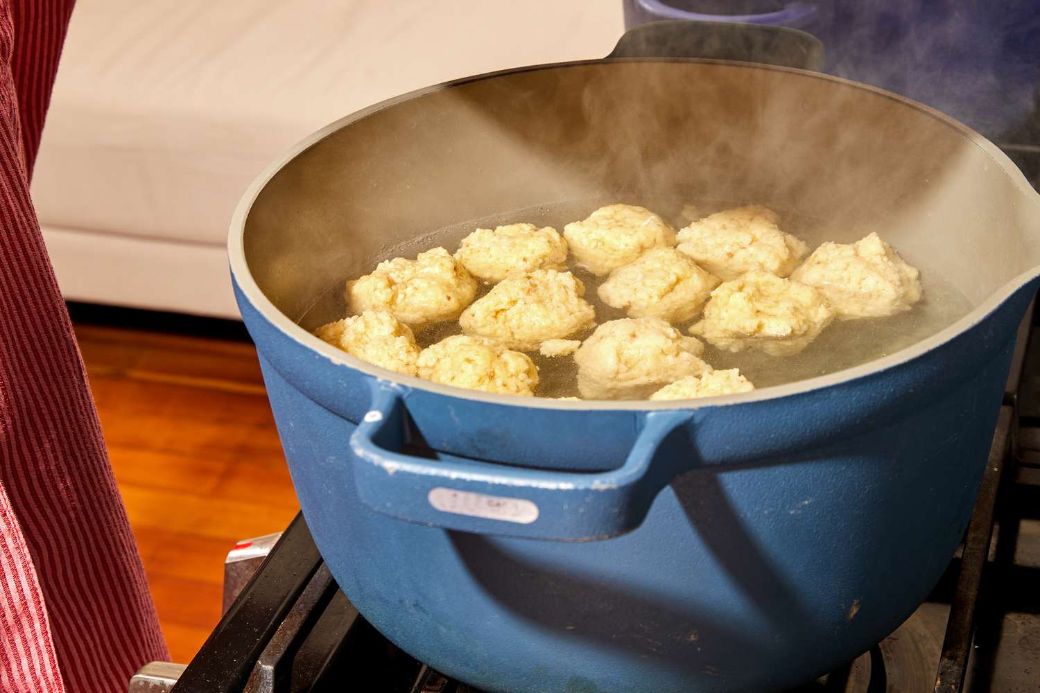 Matzo balls floating in a big blue pot of boiling water