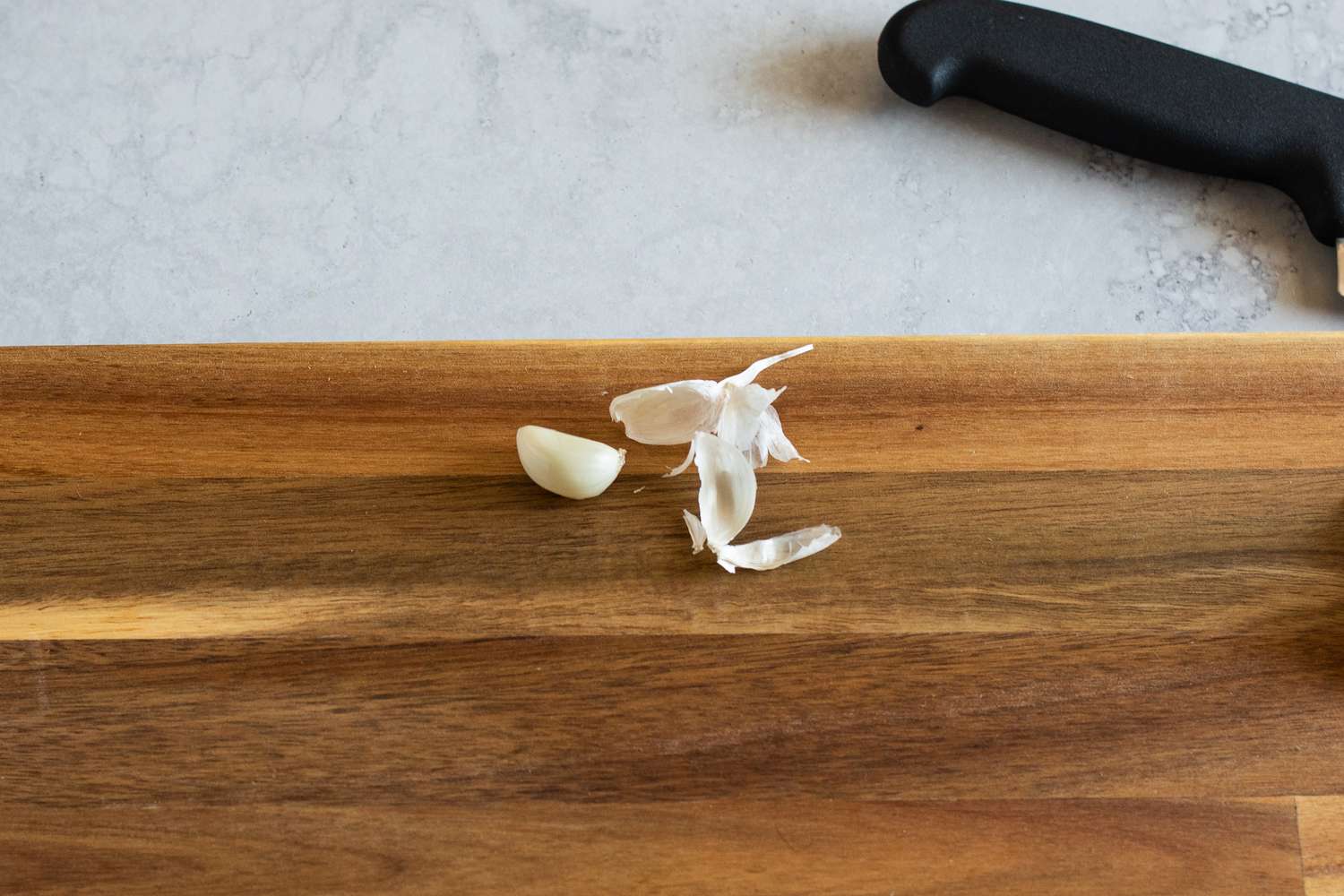 Peeled garlic cloves on a wood cutting board